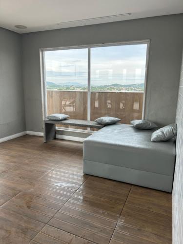 a bedroom with a bed and a large window at Flat Samba Bossa Nova in Cabo Frio