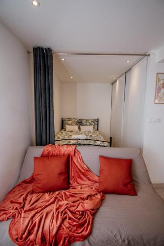 a bed in a room with two red pillows at Ecrin Pontissalien - Studio with Parking in Pontarlier