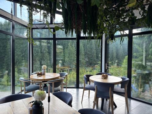 two tables and chairs in a room with windows at Шишка in Bukovel