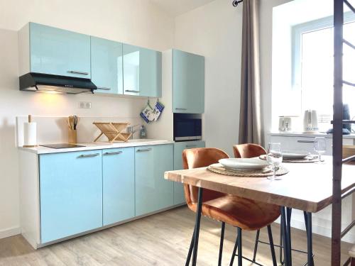 une cuisine avec des placards bleus et une table avec des chaises dans l'établissement Studio Framboises - Plage et commerces à proximité, à La Bernerie-en-Retz