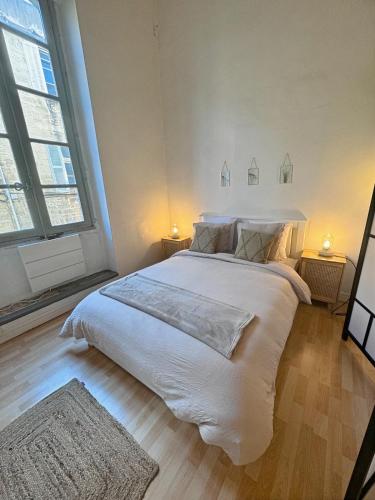 Cette chambre comprend un grand lit blanc et 2 fenêtres. dans l'établissement Le Futé - Le nid d'Avignon - WiFi - 2 chambres, à Avignon