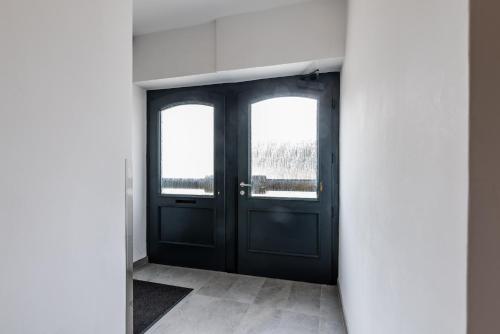 a hallway with a black door and two windows at Mariazell Penthouse Kugeltreff in Mariazell