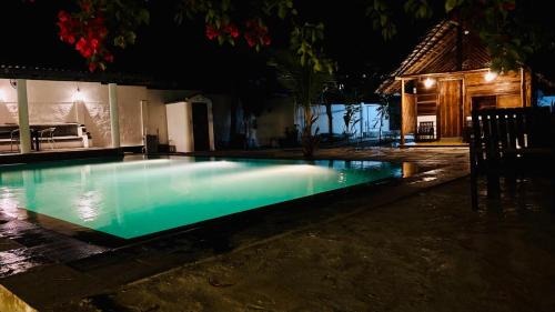 a swimming pool at night in front of a house at Pool Bay in Arugam Bay
