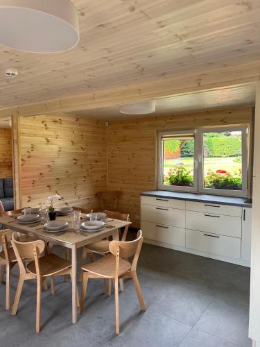 a dining room with a table and chairs and two windows at Sudecki Domek in Kudowa-Zdrój