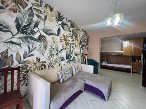 Simple Apartment في أوريكوم: غرفة معيشة بها أريكة وجدار مزين بالزهور