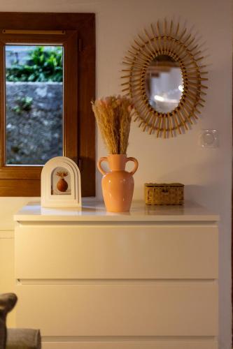 un vase posé sur une commode avec un miroir dans l'établissement La maison d'Acoya, à Valdeblore