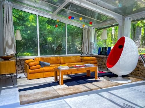 un salon avec un canapé et une grande fenêtre dans l'établissement Le Poolhouse, Lodge avec piscine au coeur du Luberon, à Saint-Saturnin-lès-Apt