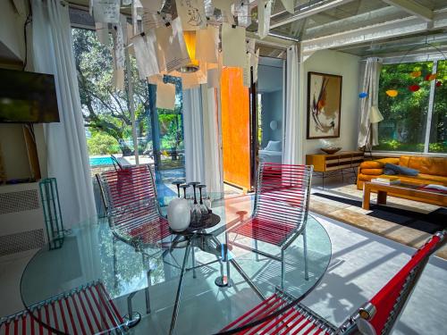 une chambre avec des chaises rouges et une table en verre dans l'établissement Le Poolhouse, Lodge avec piscine au coeur du Luberon, à Saint-Saturnin-lès-Apt