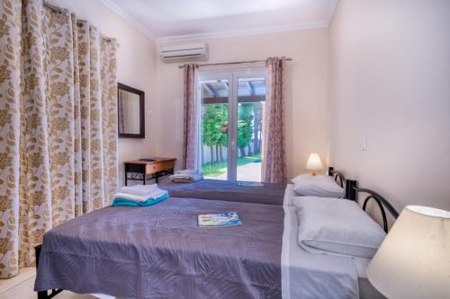 two beds in a room with a window at Villa Angela in Ágios Matthaíos