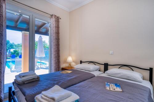 two beds in a bedroom with a view of a patio at Villa Angela in Ágios Matthaíos