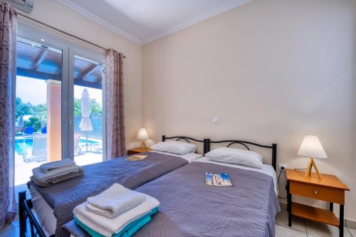 a bedroom with two beds and a large window at Villa Angela in Ágios Matthaíos
