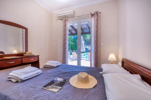 a hat sitting on a bed with a mirror at Villa Angela in Ágios Matthaíos