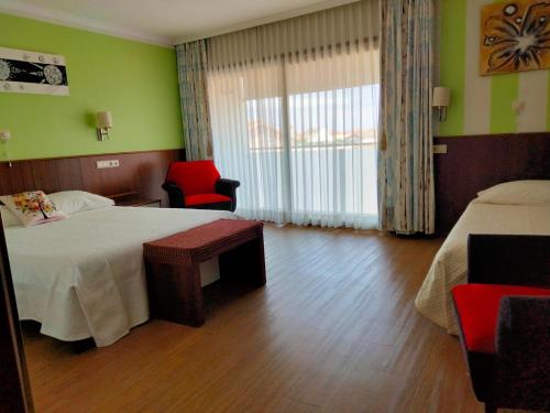 a hotel room with a bed and a chair at Alojamento Rivera in Gafanha da Nazaré