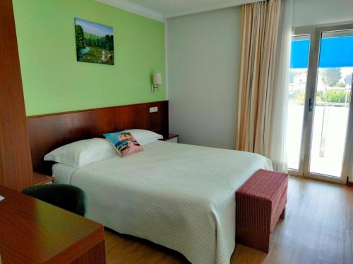 a hotel room with a bed and a table and a window at Alojamento Rivera in Gafanha da Nazaré