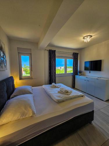 a large bed in a bedroom with two windows at Crystal Adria in Privlaka