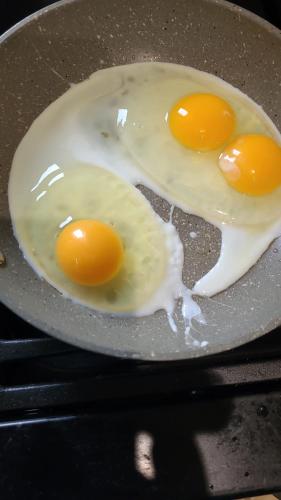 two eggs frying in a pan on a stove at Stone Lodge Bed & Breakfast in Navan