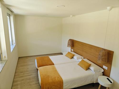 a bedroom with a bed with a wooden headboard at Pensión Lemos in Tríacastela