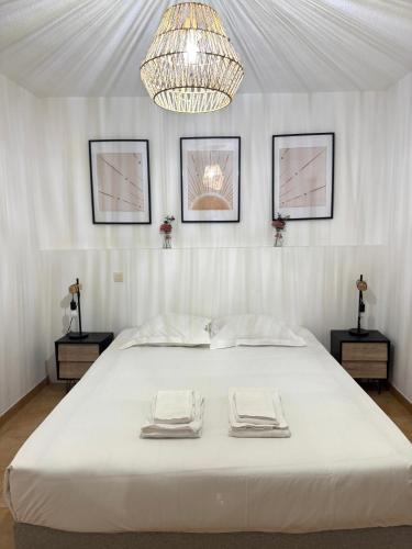 Cette chambre comprend un grand lit blanc et un lustre. dans l'établissement Residence Paolina, à Calvi