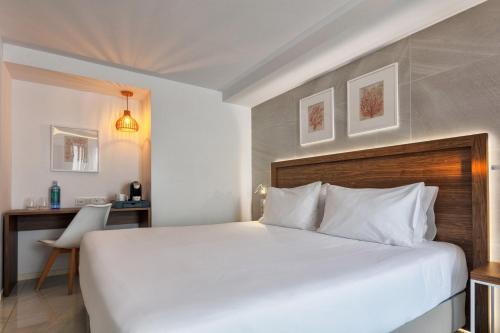 a bedroom with a large white bed and a desk at Eurostars Puerto de Ibiza in Ibiza Town