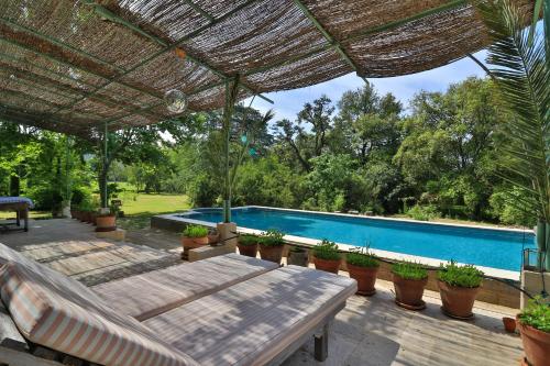 un patio extérieur avec une piscine et une pergola dans l'établissement Mas provençal authentique XXL avec grande piscine et immense jardin, à La Crau
