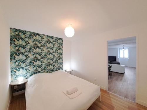 - une chambre avec un lit blanc et un mur fleuri dans l'établissement Turin - Appartement charmant et moderne, à Reims