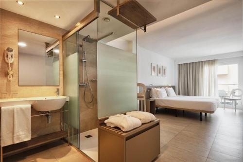 a bathroom with a sink and a shower and a bed at Eurostars Puerto de Ibiza in Ibiza Town