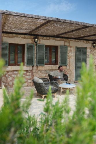 a man sitting in a chair in front of a house at Es Figueral Nou Hotel Rural & Spa - Adults Only - Over 12 in Montuiri