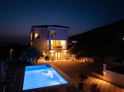 a large swimming pool in front of a house at night at Villa Mianka Rab in Banjol