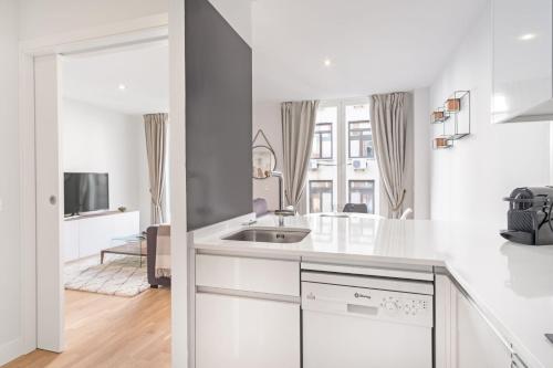 Biała kuchnia ze zlewem i salon w obiekcie Charming 1-Bedroom Apartment in Central Madrid Stylish Retreat for 2, Alonso Martinez I w Madrycie
