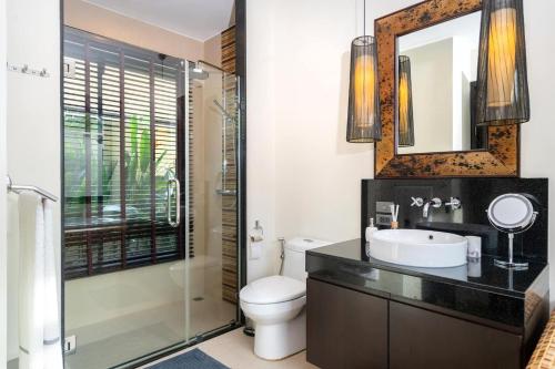 Un baño con inodoro, lavabo y espejo. en Luxury Tropical Garden Pool Villa, en Rawai Beach