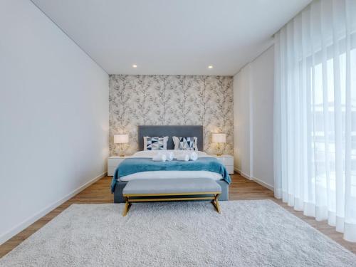 a bedroom with a blue bed and a large window at Vita Portucale ! Chic Luxe Villa with Saltwater Pool in Corroios
