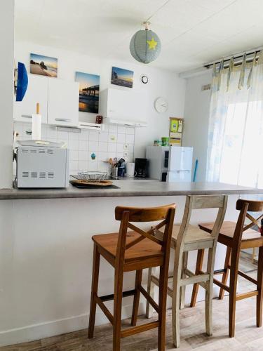 - une cuisine avec 2 chaises et un comptoir dans l'établissement Votre pied à terre à proximité des dunes, à Berck-sur-Mer