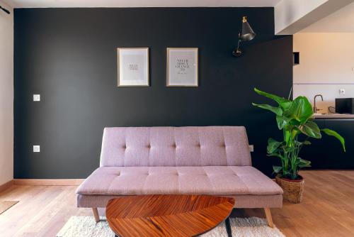 a couch in a living room with a black wall at L'élegant, climatisé et rénové - Appart'hôtel Chez MV in La Ferté-Gaucher