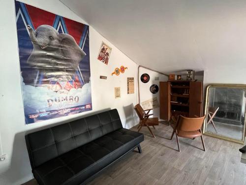 un salon avec un canapé noir et une affiche d'éléphant dans l'établissement Les Secrets de Madeleine, à Ginestas