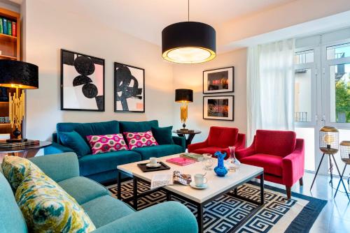 a living room with blue couches and red chairs at Genteel Home Albareda in Seville