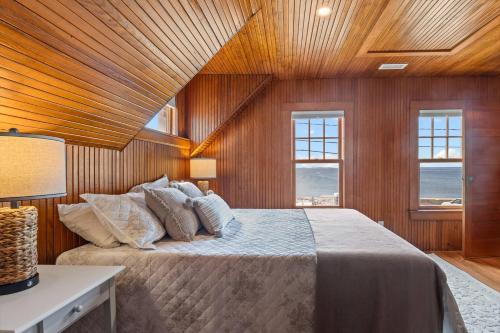 a bedroom with a bed with wooden walls and windows at Life of Reilly - Scituate in Scituate