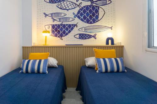 twee bedden in een kamer met blauwe en gele kussens bij Las Palmeras BlueFish in Benalmádena