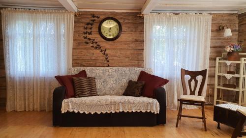 a living room with a couch and a clock on the wall at Authentic homestead over 100 years old in Kėdainiai