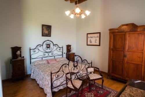 a bedroom with a bed and two chairs and a chandelier at Villa Bongiovanni in San Bonifacio