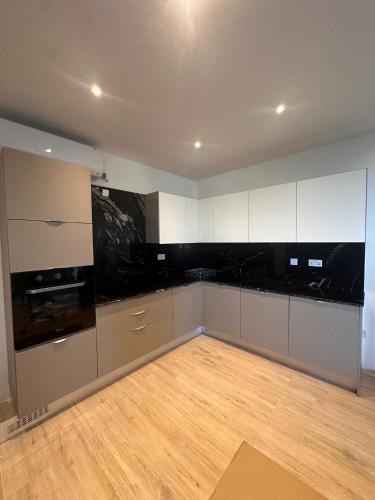 a kitchen with white cabinets and a wooden floor at One Bedroom in New Apt Mellieha- Blue Room 2 in Mellieħa