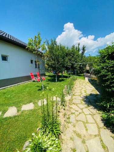 a garden with two red chairs and a stone path at Agropa Rooms & Garden Events in Bistriţa