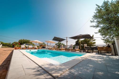 a swimming pool with chairs and umbrellas on a patio at Villa Mianka Rab in Banjol