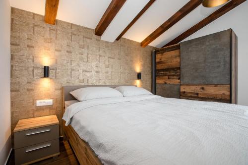 a bedroom with a large bed and a brick wall at Gabriel Home in Rab