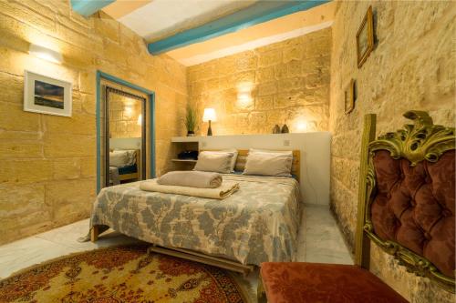 a bedroom with a bed in a stone wall at Cosy Haven, 96 Triq il-Karita', Victoria Gozo in Victoria