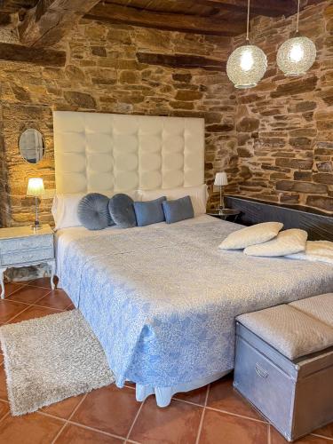 a bedroom with a large bed in a stone wall at Complejo Rural Lar de Vies in A Pontenova