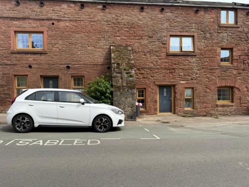 a white car parked in front of a brick building at Fairladies Barn Guest House in St Bees