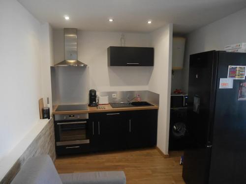 La cuisine est équipée d'un réfrigérateur noir et d'un évier. dans l'établissement Pleasant air-conditioned T2 apartment in Ile Rousse, à LʼÎle-Rousse