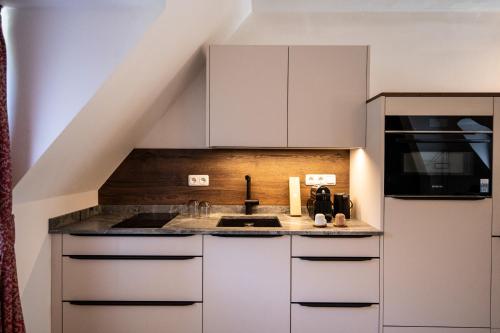 a kitchen with white cabinets and a sink at Schloss Hantberg Apartments 