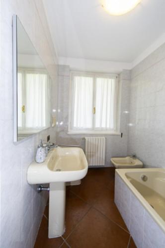 a bathroom with a sink and a tub and a mirror at Villa Oliva in Tremezzo