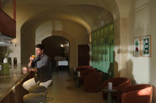 a man sitting at a bar with a glass of wine at Es Figueral Nou Hotel Rural & Spa - Adults Only - Over 12 in Montuiri